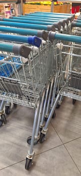 A row of empty shopping carts lined up neatly in a grocery store aisle, ready for customers to use.