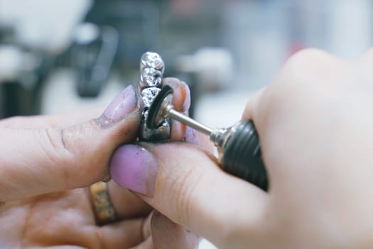 A dental technician is seen working on a toothbrush component in a room, using tools and equipment to manufacture the metal prosthesis.