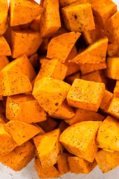 Seasoning cubed sweet potatoes to make oven-roasted sweet potatoes.