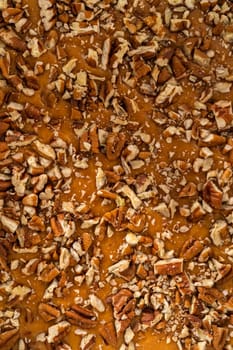 Pouring fudge mixture into the square glass baking pan lined with parchment paper to prepare pumpkin spice fudge.