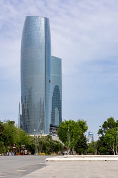 A tall building with a lot of windows and a large glass facade. The sky is clear and the sun is shining