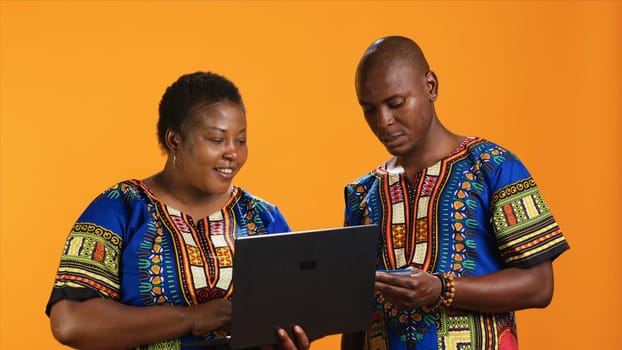 African american woman buying clothes online on laptop, doing shopping session and typing credit card details on webpage. Married couple looking at items on sale, banking purchase.