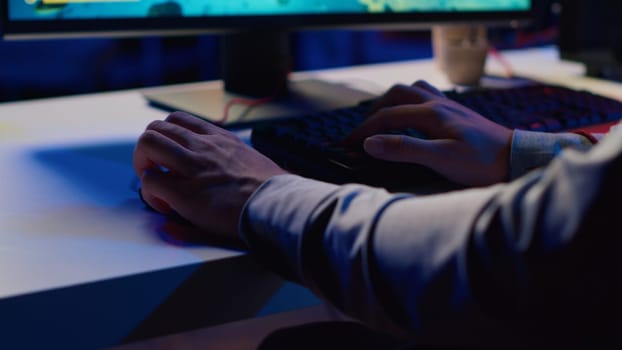 Gamer plays online multiplayer spaceship videogame, defeating rivals, close up shot. Player enjoying leisure time in neon lights adorn living room, flying spacecraft using gaming computer peripherals