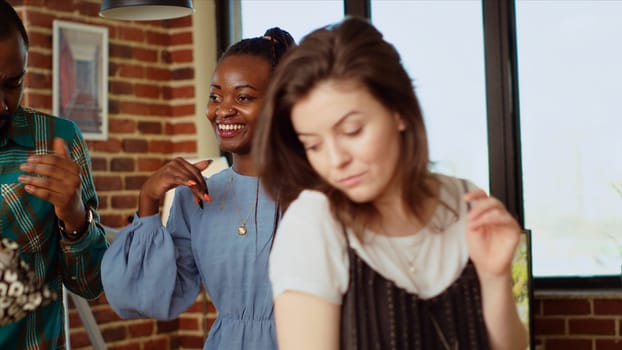 Close up shot of merry friends dancing at house party while drinking wine glasses, enjoying celebration. Multiethnic group of people having fun, doing skillful dance moves to music in apartment