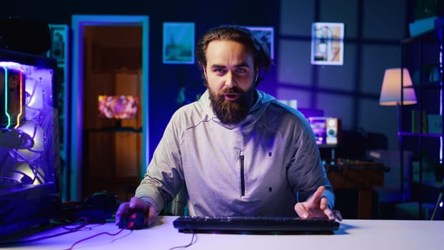 Content creator turning gaming chair around, greeting audience, filming tutorial on how to defeat enemies in multiplayer game. Pro gamer playing videogame, teaching viewers esports strategies
