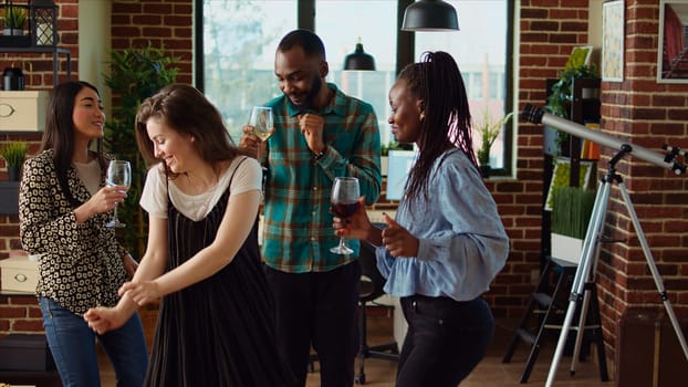 Diverse mix of guests at home party sharing laughter and dance moves in living room, dolly in shot. Friends dancing on disco beats during weekend hangout, shaking their shoulders