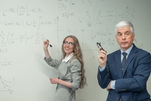 Female student answers a question from an elderly professor at a white board