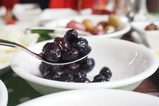 closeup of spoon pick black olives .