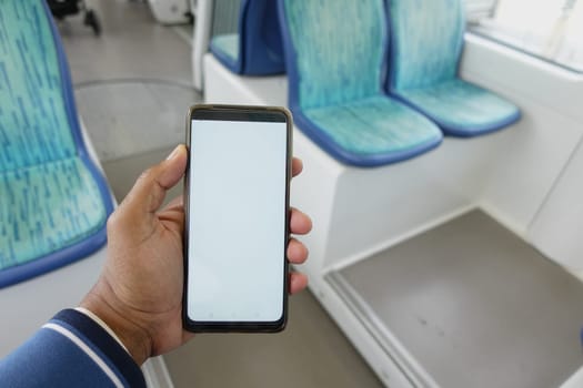 young man hand using smart phone with white screen inside of metro train.