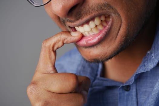 young men biting his nails at home