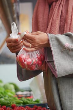 women Choose ripe tomato in market,