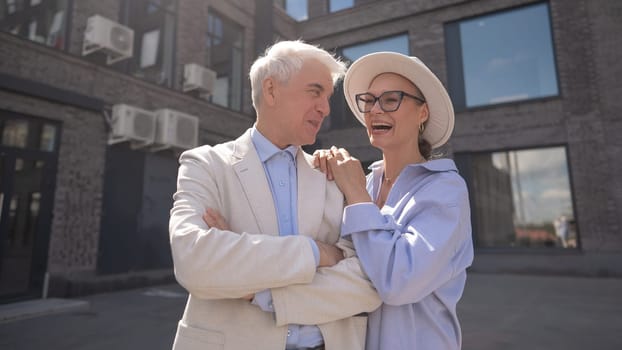 An elderly couple in love walks through the city. Portrait of a stylish gray-haired man and woman