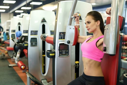 At fitness room. Image of sexy girl exercising on simulator