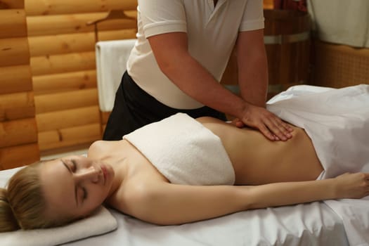 In spa center. Image of masseur massaging girl's belly