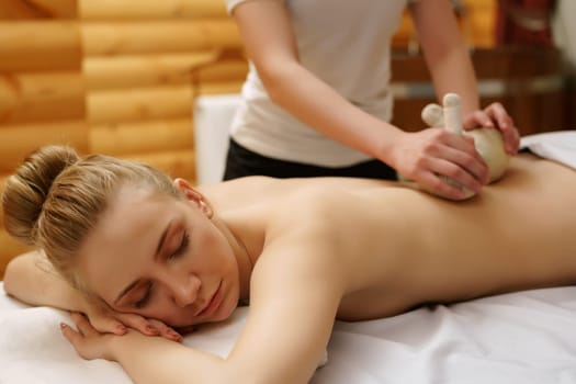 In spa center. Girl relaxes during massage with salt bags