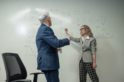 Female student answers a question from an elderly professor at a white board