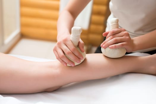 Masseuse doing thai massage with salt bags, close-up