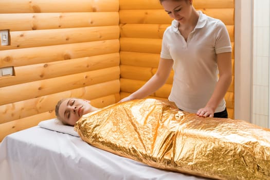 Body wraps. Photo of pretty girl relaxing in spa salon