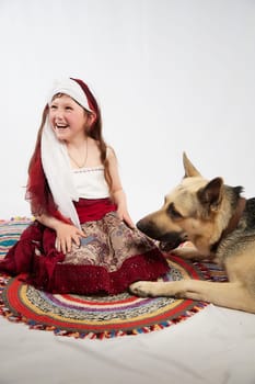 Portrait of Little girl in a stylized Tatar national costume with big shepherd dog on a white background in the studio. Photo shoot of funny young teenager who is not a professional model