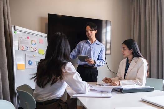 Young Asian business team discussing data analysis in modern office.