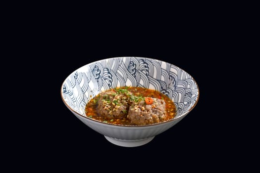 Scalded meatballs in spicy soup isolate on black background. Asian food.