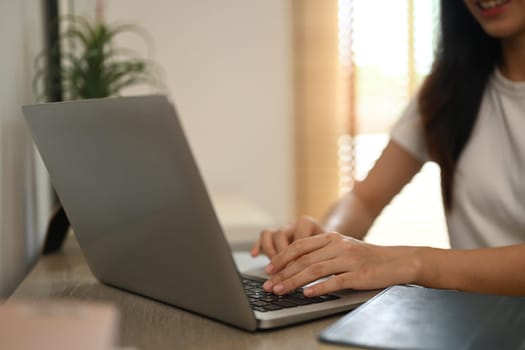Hand of young female typing on laptop keyboard, working online or searching information.