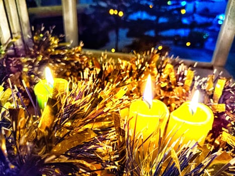 Candle burning amidst holiday decorations. Festive Candles Lighting Up Christmas-Adorned Room at Night