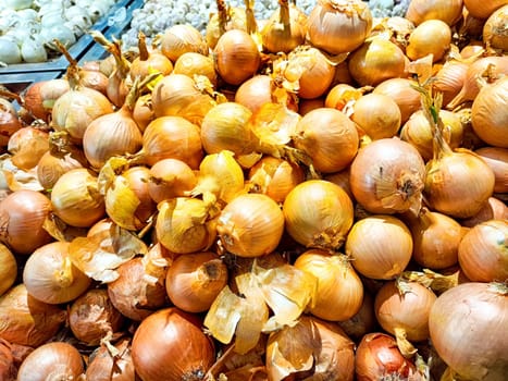 Fresh onions spread out for customers at a market. Pile of Fresh Onions for Sale at Local Market Stall