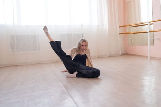 Caucasian woman dancing contemporary on the floor in a ballet class