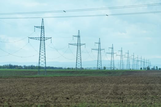 High voltage towers with sky background. Power line support with wires for electricity transmission. High voltage grid tower with wire cable at distribution station. Energy industry, energy saving.