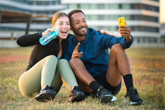 happy young couple using smartphone and sports bottle in hand to take self portrait.