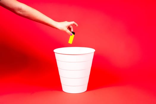 The old lighter is thrown into a trash basket. Red background, selective focus, copy space.