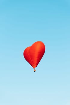 romantic heart shaped hot air balloon soaring through clear blue sky on a sunny day