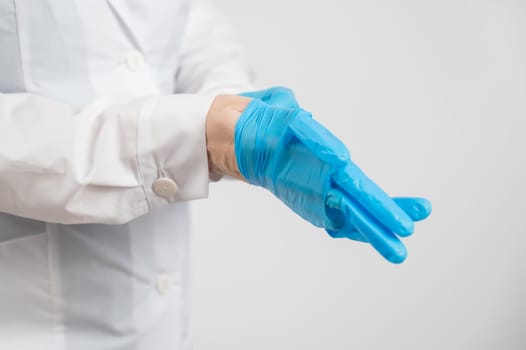 The doctor puts on latex gloves on a white background