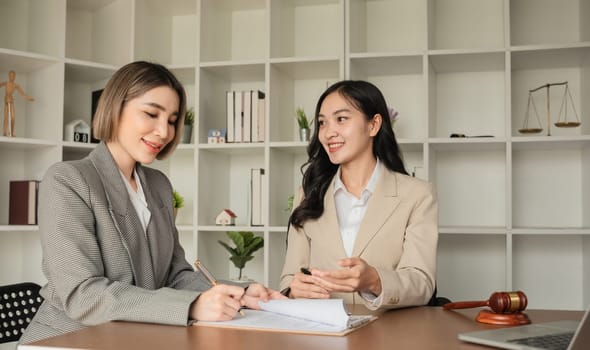 Two Asian businesswomen working together at office desk. Concept of business teamwork and professional collaboration.