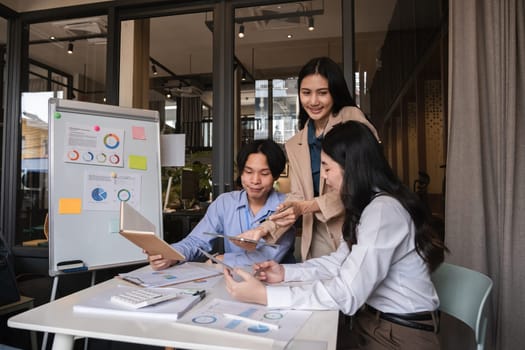 Young Asian business team discussing data analysis in modern office.