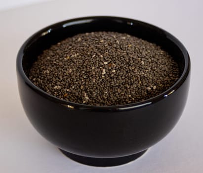Chia seeds in black bowl. Vegan food. Source of minerl and vitamins. Healthy seeds food concept