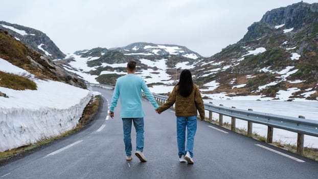 a couple of men and woman on a snowy road, a diverse couple at the Lyse road covered with snow to Krejag Norway Lysebotn, a road covered with snow in Spring