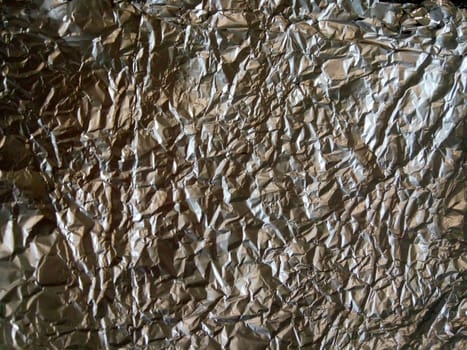 A Thin Leaf on a Silver Leaf Background with a Shiny, Wrinkled, Uneven Surface. Picture of Horizontal Aluminum Paper Crease.