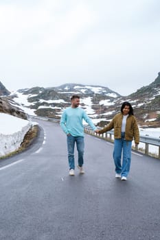a couple of men and woman on a snowy road, a diverse couple at the Lyse road covered with snow to Krejag Norway Lysebotn, a road covered with snow in Spring