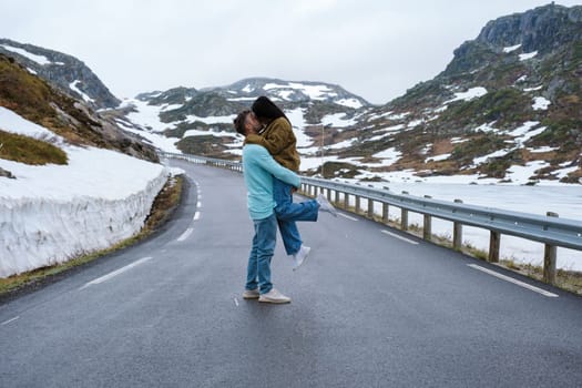 a couple of men and woman on a snowy road, a diverse couple at the Lyse road covered with snow to Krejag Norway Lysebotn, a road covered with snow in Spring in Norway