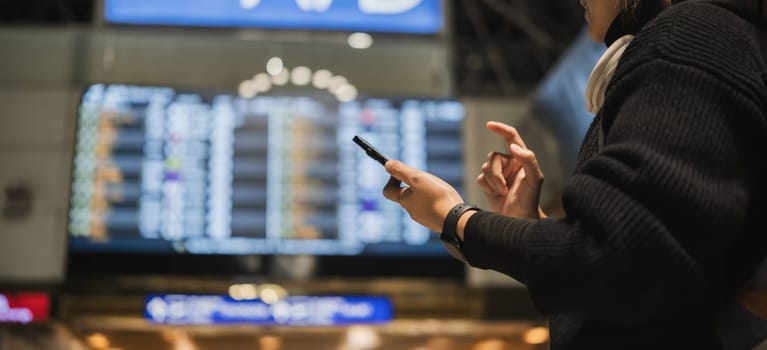 Close-up of woman checking phone at airport terminal, Concept of travel and technology.