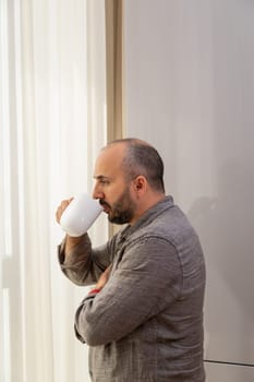 A man enjoys his morning coffee by the window