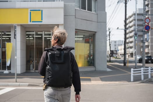 Man with backpack walking in urban city street. Concept of exploration and city travel.