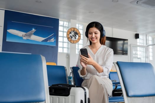 Young woman listening to music on smartphone at airport. Concept of travel and leisure.