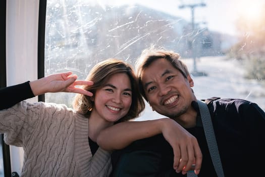 Smiling couple posing inside cable car. Concept of joy and travel.