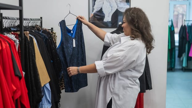 Smiling Caucasian fat woman chooses clothes for the holiday. Plus size store