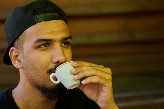 A close up capture of a Middle Eastern teenager indulging in a moment of coffee enjoyment, reflecting on relaxation and cultural affinity.