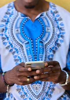 African American teenager adorned in traditional Sudanese clothing, seamlessly navigating the digital world with a smartphone in hand.