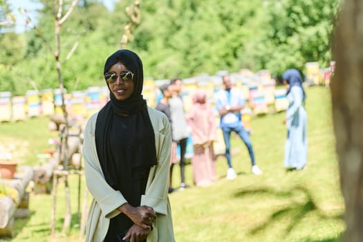 African American Muslim woman in hijab explores natural bee farms for honey production, blending tradition with sustainability in the serene countryside.